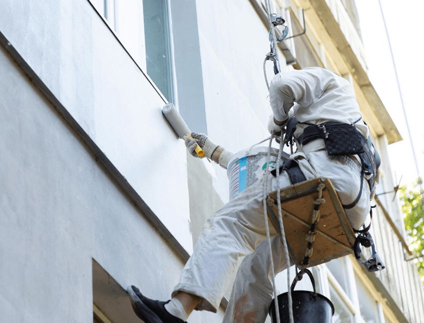 painting the exterior of a building with a roller